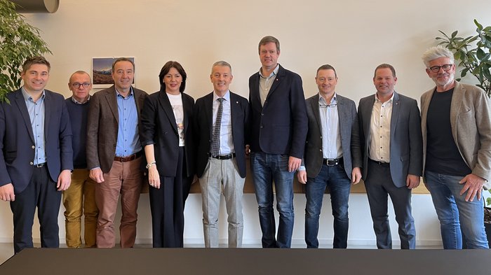 Zukunft des Handwerks: Strategische Gespräche zwischen lvh und Landesrat Peter Brunner Zehn Geschäftsleute stehen in einem Büro vor einer Wand und lächeln