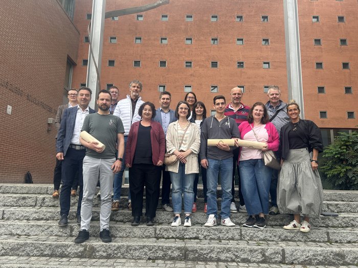 Obiettivi formativi comuni: lvh.apa e il Centro di formazione professionale Luis Zuegg di Merano rafforzano la collaborazione Gruppo di 15 persone su scale davanti a edificio rosso