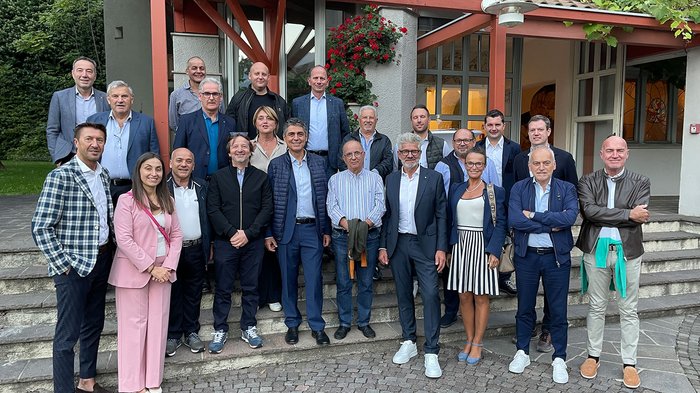 In visita a Bolzano Foto di gruppo di 22 persone davanti a un edificio con tettoia rossa in legno