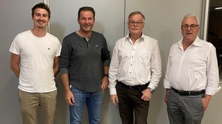 News Vier Männer posieren vor grauer Wand