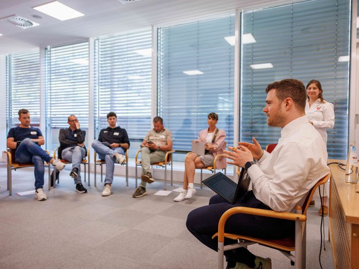 Zukunft gestalten mit KI: Die „KI-Tage 2025“ in Bozen setzen neue Maßstäbe im Handwerk Gruppe von Menschen in Stuhlkreis bei einer Besprechung in einem hellen Büro