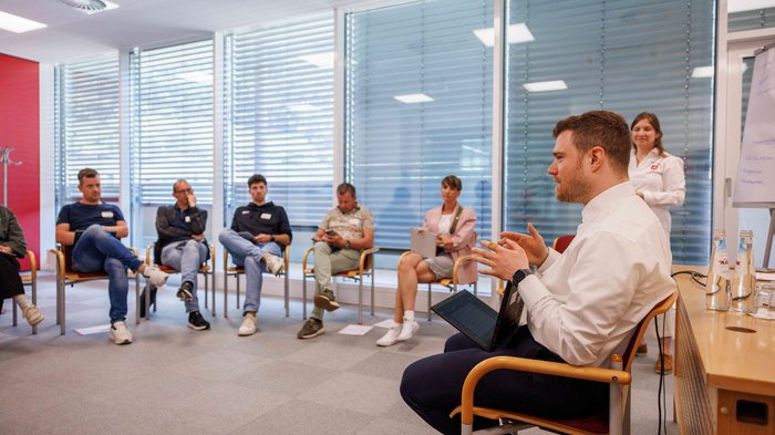 Dare forma al futuro con l'Intelligenza Artificiale: Le "Giornate dell'IA 2025” di Bolzano stabiliscono nuovi standard nel settore dell'artigianato Gruppo di persone sedute in cerchio in una riunione in un ufficio luminoso