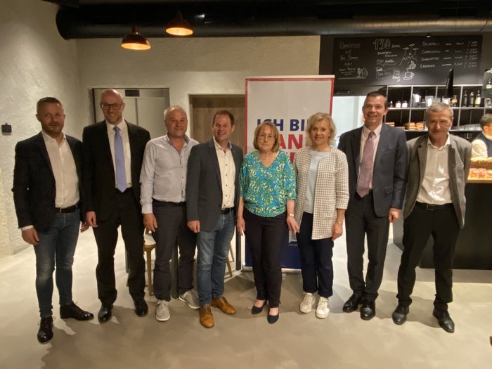 Ziehen alle an einem Strang: Handwerker/innen im Wipptal Gruppe von acht Personen in formeller Kleidung in einem Innenraum vor einem Werbebanner