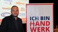 Südtiroler Tiefbauunternehmer/innen: Michael Hofer als Obmann bestätigt Mann steht neben Schild mit Schrift Ich bin Handwerk