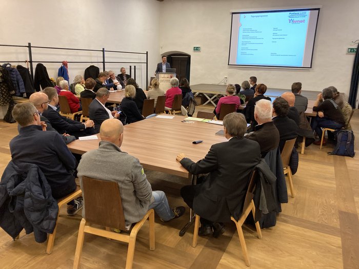 Die Zukunft der Gesundheitsversorgung ist eine Gemeinschaftsaufgabe Teilnehmer bei einem Vortrag in einem Konferenzraum mit Projektor