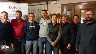 News Gruppe von acht Personen steht gemeinsam vor einem lvhapa-Banner in einem Raum.