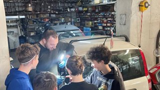 News Mann zeigt Gruppe junger Männer Autoteile in einer Garage
