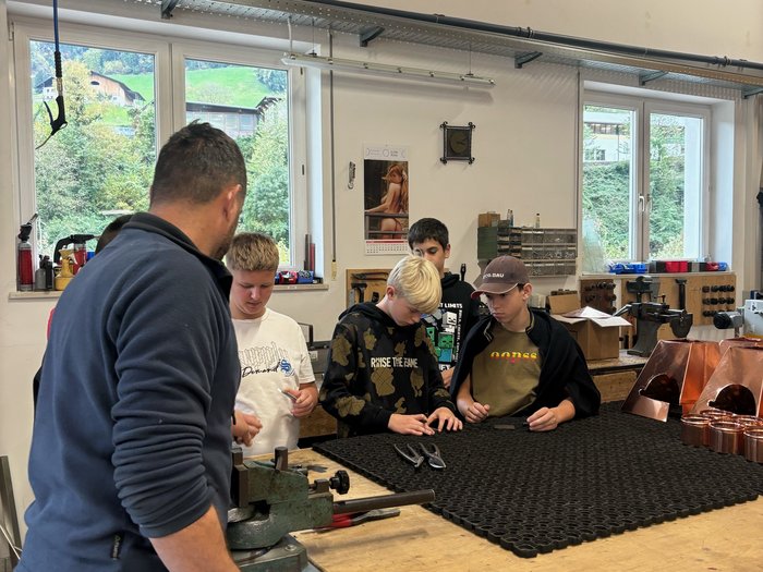 Campagna informazione carriere San Martino in Passiria Adulto mostra attrezzi e banco di lavoro a ragazzi in officina
