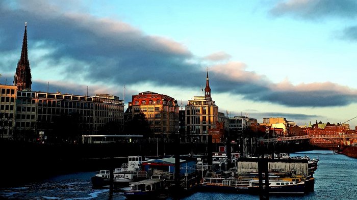 Die Althandwerker besuchen Hamburg Hafen mit Booten und Gebäuden bei Sonnenuntergang unter blauem Himmel