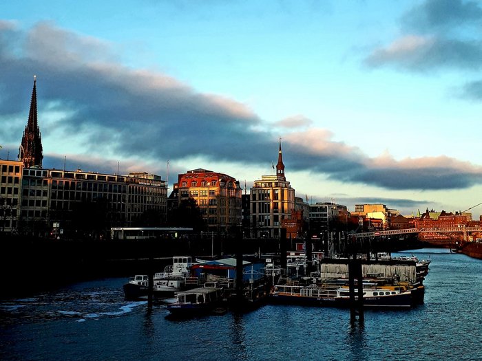 Die Althandwerker besuchen Hamburg Hafen mit Booten und Gebäuden bei Sonnenuntergang unter blauem Himmel