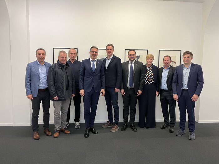 lvh-Spitze auf Antrittsbesuch bei Kompatscher und Galateo Neun Personen in Anzügen stehend vor einer weißen Wand mit Bildern