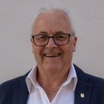 Bozen Land Porträt eines älteren Mannes mit Brille, Anzugjacke und Hemd vor weißer Wand