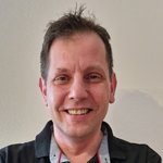 Bozen Land Lächelnder Mann mit kurzem braunem Haar vor heller Wand