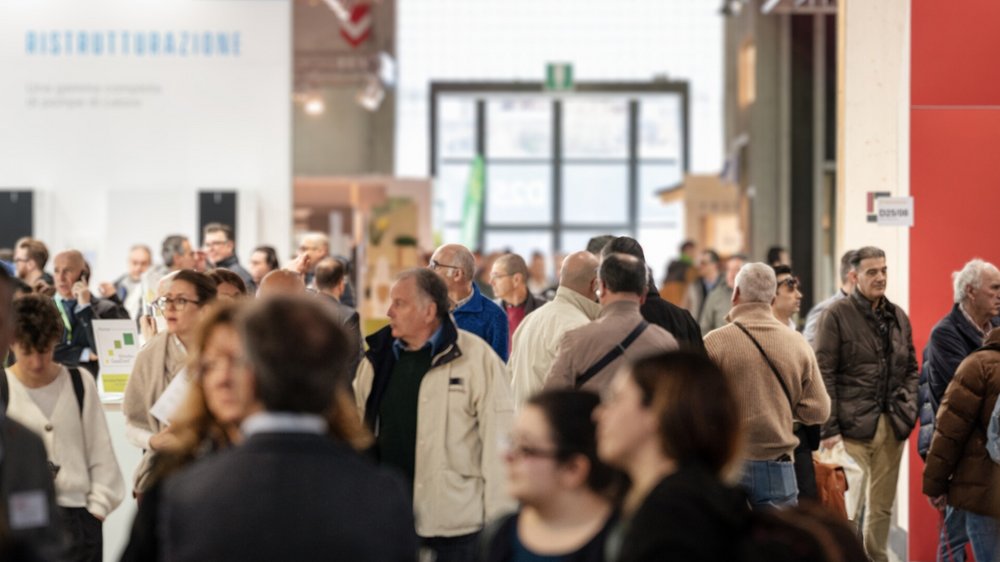 Home Molte persone camminano in un affollato padiglione fieristico