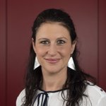 Bozen Land Porträt einer lächelnden Frau mit dunklen Haaren vor rotem Hintergrund