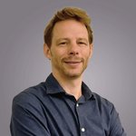 Das lvh-Team Porträt eines lächelnden Mannes mit blauem Hemd vor grauem Hintergrund