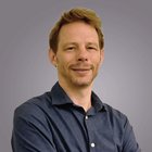 Riviste Ritratto di uomo sorridente con camicia blu su sfondo grigio