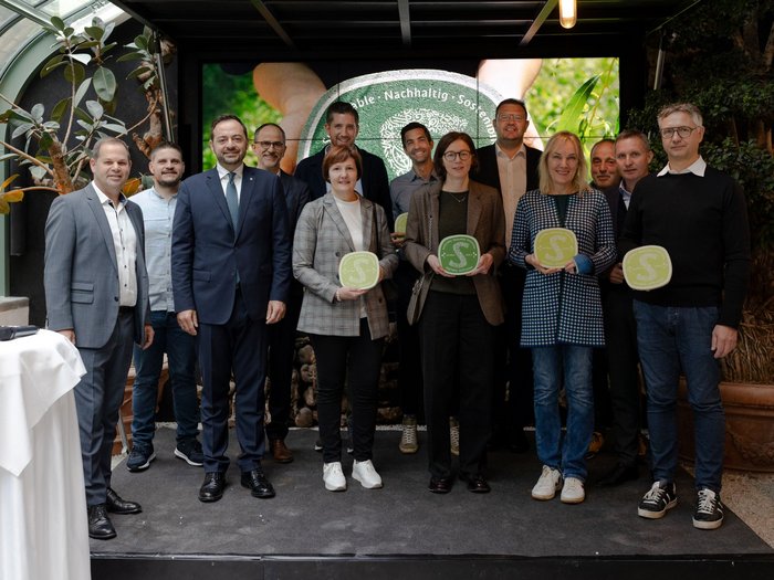 Nachhaltigkeitslabel Südtirol Gruppenfoto von zwölf Personen bei einer Auszeichnung mit nachhaltigen Zertifikatstafeln