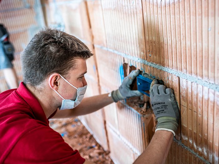 Green Pass: vielleicht schon bald Erleichterungen für Unternehmen Handwerker mit Mundschutz montiert Steckdosenrahmen in Ziegelwand