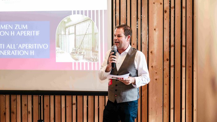 Consegna della spilla d’oro di lvh.apa Uomo con microfono davanti a schermo di proiezione durante presentazione