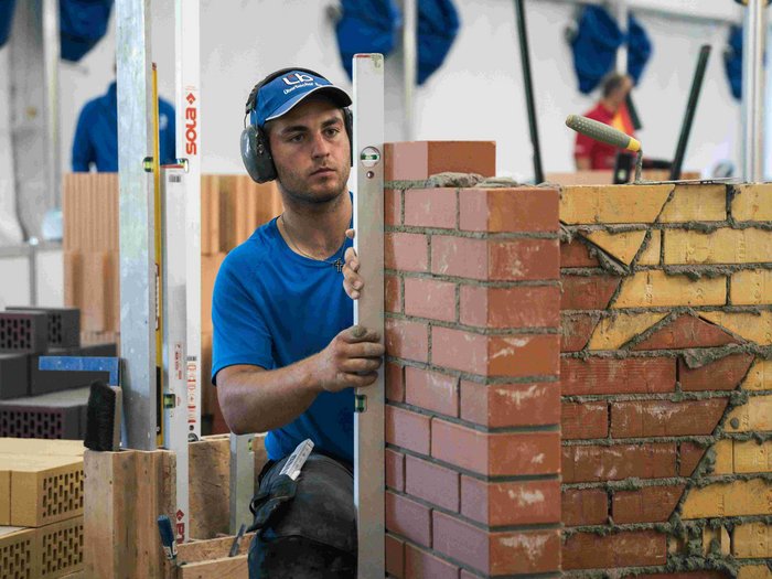 EuroSkills 2023: adesso bisogna concentrarsi! Muratore controlla con livella una parete in mattoni