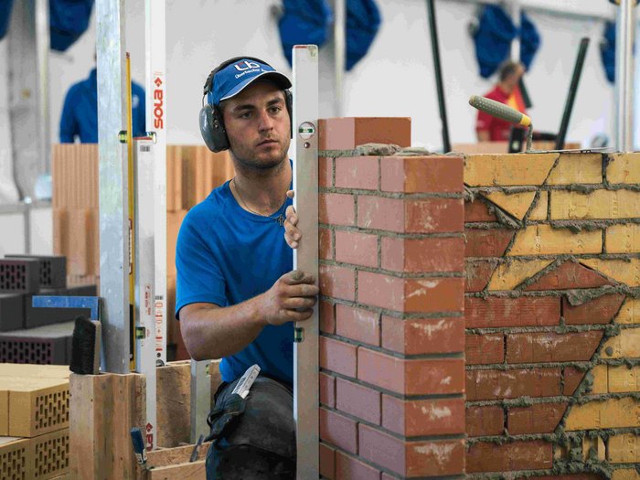 EuroSkills 2023: adesso bisogna concentrarsi! Muratore controlla con livella una parete in mattoni