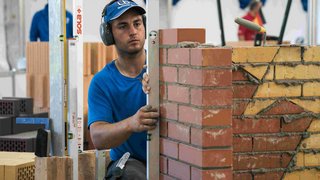 News Maurer prüft mit Wasserwaage eine Klinkerwand