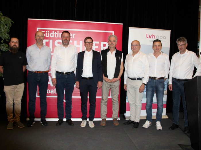 Fachkräftegewinnung im Fokus Gruppenfoto von neun Männern bei einer Tischlerveranstaltung vor Bannern