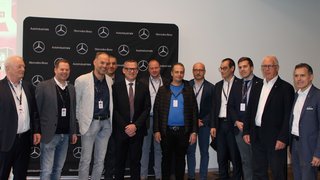 News Gruppo di dodici uomini davanti a sfondo Mercedes-Benz e Autoindustriale