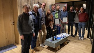 News Gruppe von elf Personen in einem Holzraum, zwei halten Urkunden