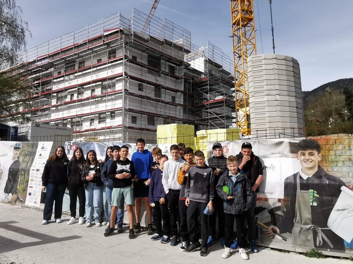 L’artigianato come materia a scelta Gruppo di adolescenti davanti a un cantiere con impalcature e gru