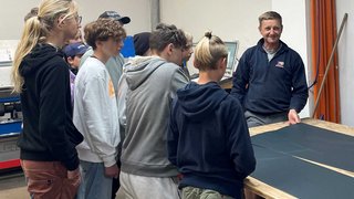 News Gruppe Jugendlicher hört einem Mann bei einer Vorführung in einer Werkstatt zu