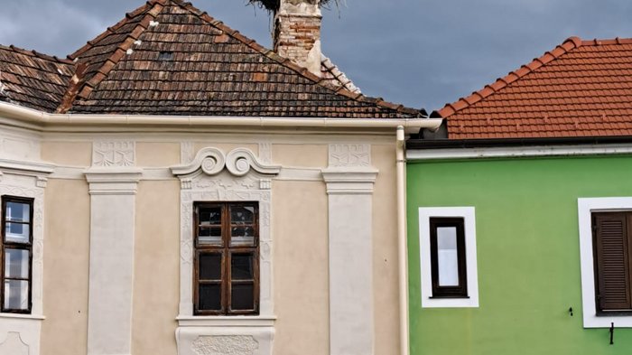 Viaggio culturale nel Burgenland – Opera e musical come fulcro del programma Cicogne nidificano su un camino sopra un caffè con cielo nuvoloso