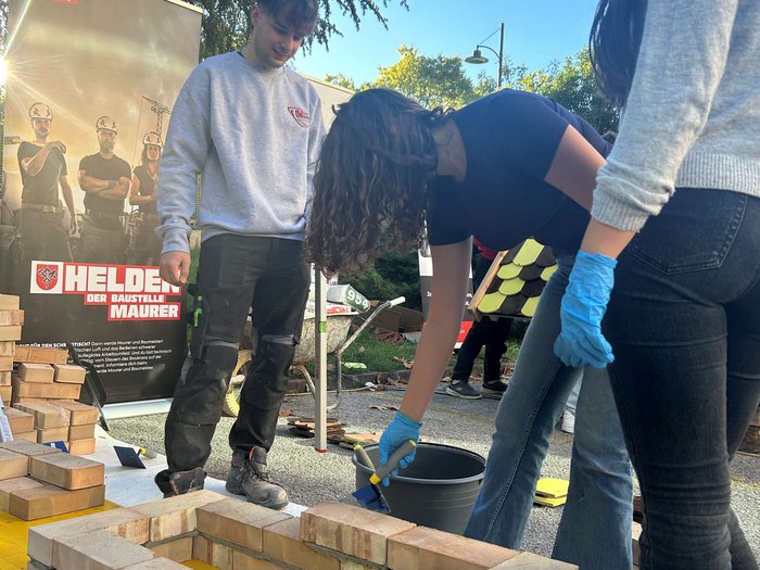 SkillsDay in Lana: Schüler/innen erleben Handwerk hautnah Jugendliche mauern zusammen einen Ziegelbau bei sonnigem Wetter
