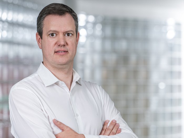 Sicurezza sul lavoro: le nuove misure devono essere concrete e differenziate Uomo con camicia bianca in piedi con le braccia incrociate davanti a parete di vetro