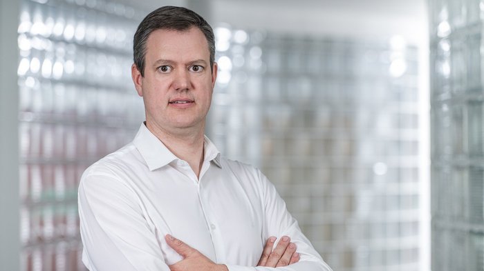 Sicurezza sul lavoro: le nuove misure devono essere concrete e differenziate Uomo con camicia bianca in piedi con le braccia incrociate davanti a parete di vetro