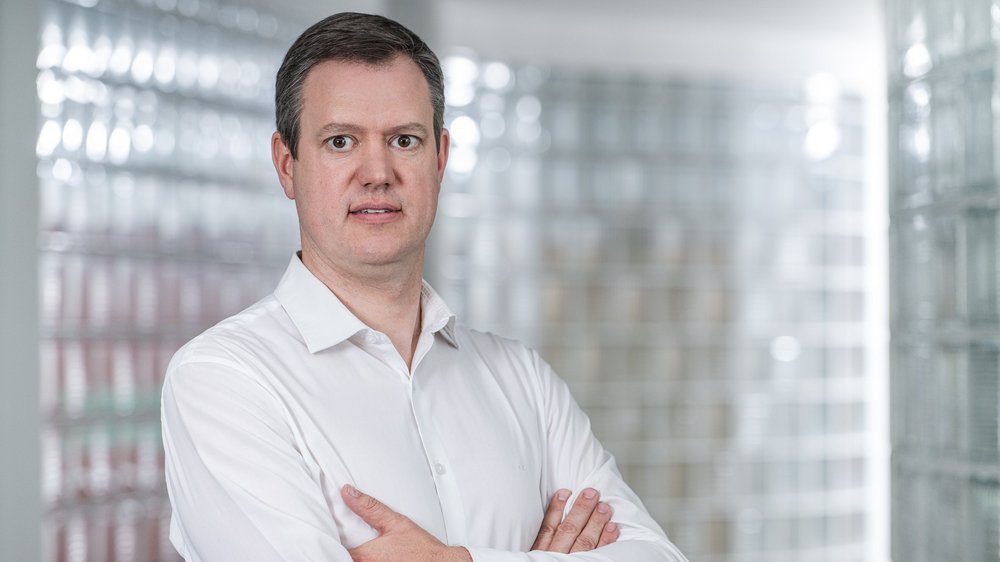 Home Uomo con camicia bianca in piedi con le braccia incrociate davanti a parete di vetro