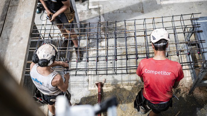 Subappaltare non deve compromettere la sicurezza sul lavoro Operai edili con caschi montano armatura in acciaio in cantiere vista dallalto