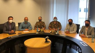 News Sechs Männer mit Masken an einem runden Konferenztisch in einem Büro