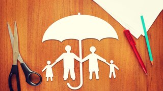 Webinare Papierfamilie unter einem Schirm auf Holztisch mit Schere, Stift und Papier