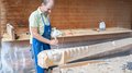 55 Jahre Schutzmarke für das Südtiroler Kunsthandwerk Mann schnitzt Holzkunstwerk in Werkstatt mit Hammer und Meißel