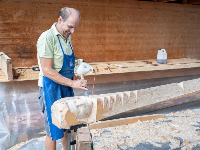 55 anni del marchio di tutela per l’artigianato artistico dell’Alto Adige Uomo intaglia scultura in legno in laboratorio con martello e scalpello