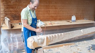 News Mann schnitzt Holzkunstwerk in Werkstatt mit Hammer und Meißel