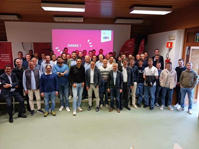 Erfolgreiche Jahresversammlung: Ein Blick in die Zukunft der Heizungs-, Lüftungs- und Sanitärtechnik Gruppenfoto von circa 40 Personen vor einer Leinwand mit Danke-Botschaft