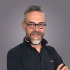 Dieter Überbacher Ritratto di uomo sorridente con occhiali e barba grigia su sfondo grigio