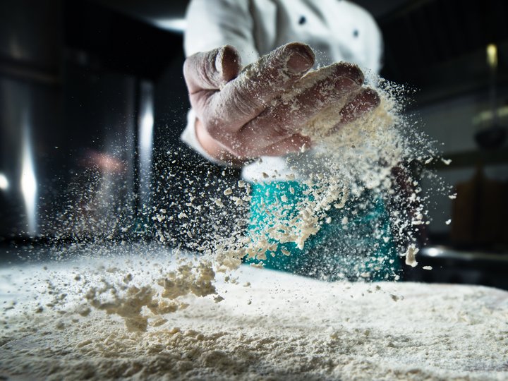 Panettieri Cuoco lancia farina in aria in cucina professionale