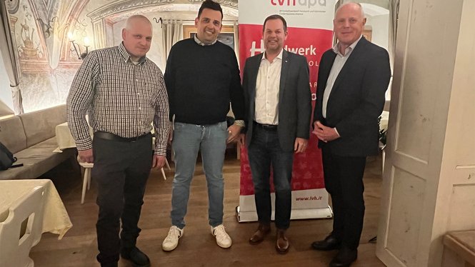 Home Quattro uomini in piedi davanti a uno striscione lvhapa in una stanza decorata