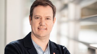 Martin Haller © Florian Andergassen Porträt eines lächelnden Mannes in Business-Kleidung mit verschränkten Armen