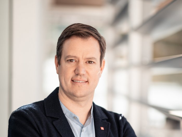 Martin Haller © Florian Andergassen Porträt eines lächelnden Mannes in Business-Kleidung mit verschränkten Armen