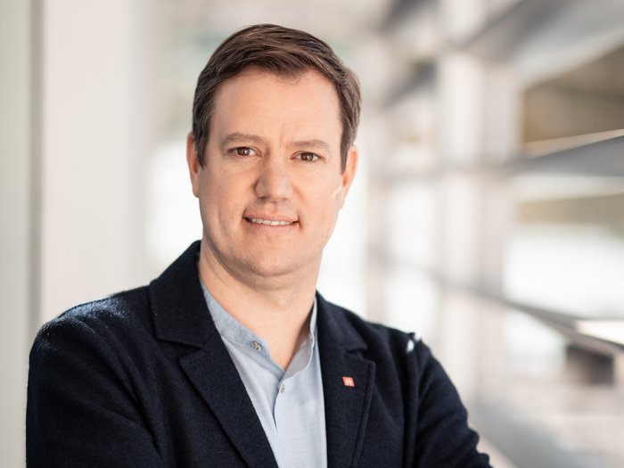 Martin Haller © Florian Andergassen Porträt eines lächelnden Mannes in Business-Kleidung mit verschränkten Armen